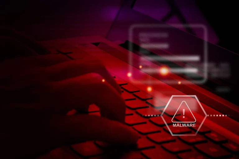 user typing on their keyboard with a malware alert sign